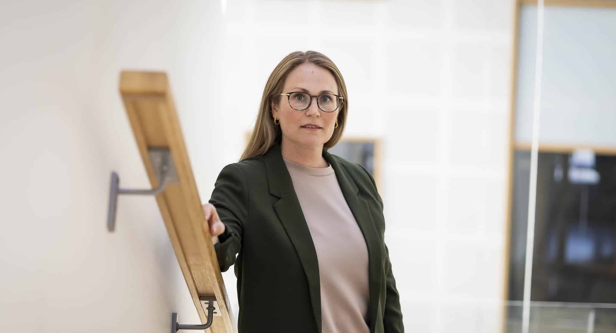 Bilde av Lene Knapstad. Dame i grøn dressjakke og lys gensar. Står i trappa og ser alvorleg i kamera.